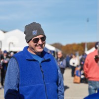 Man in sunglasses and beanie hat smiling as he talks to a woman